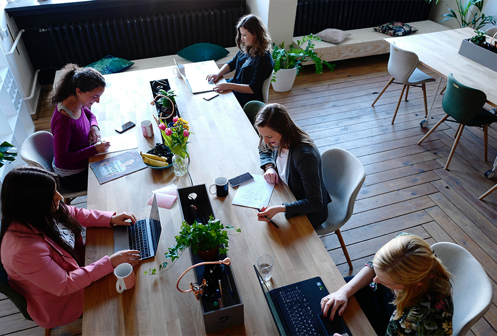 People working on laptops at table in co working space.