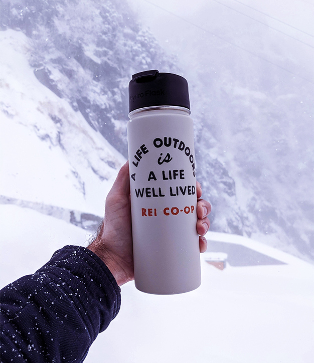 Person outdoors in snow holding water bottle that reads 