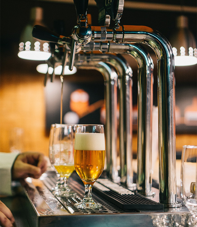 People pouring beers from tap at brewery.