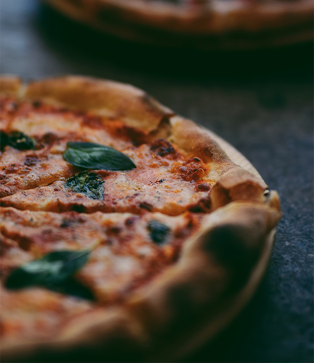 Detail of wood fired pizza with cheese and basil.